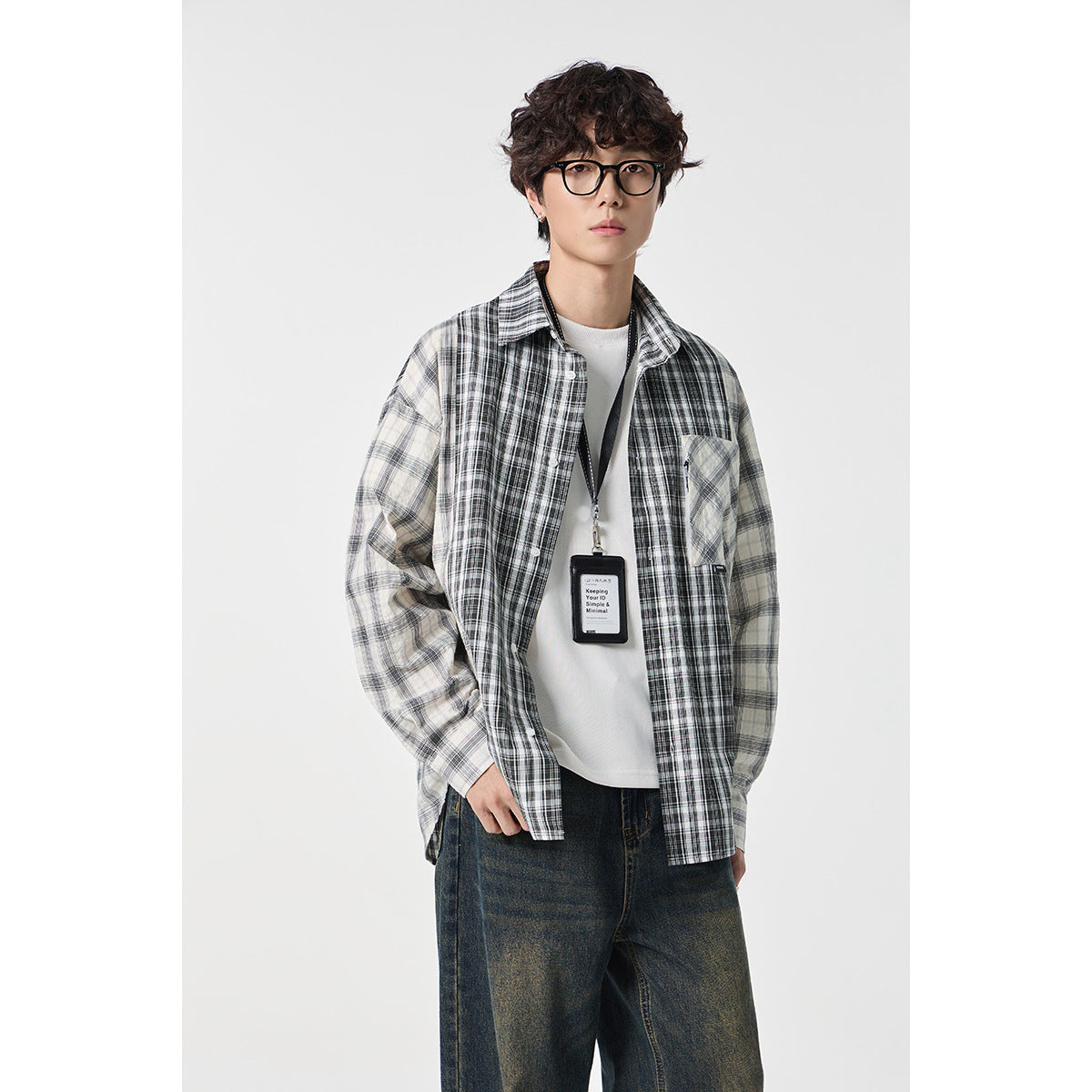 Model wearing a buttoned gray-and-black plaid shirt over a white tee, with a black lanyard and ID card.