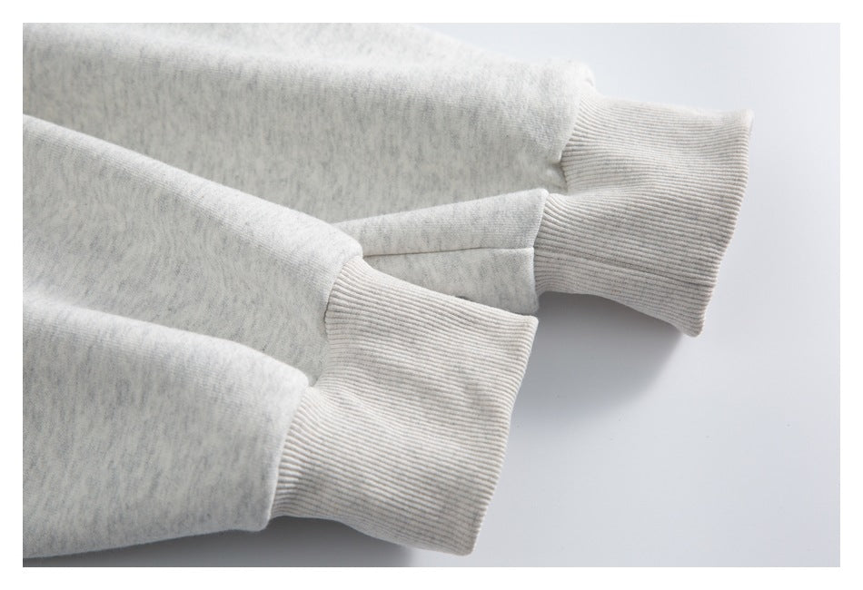 Close-up of a light heather-gray sweatshirt sleeve with wide ribbed cuffs.