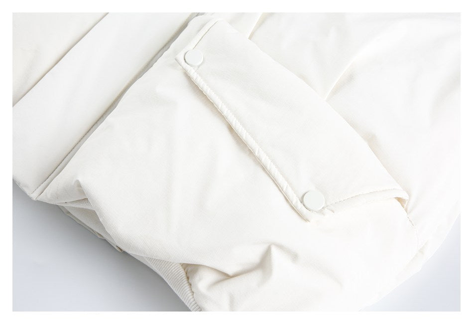 Close-up of an ivory garment's snap-button cuff tab and stitching.
