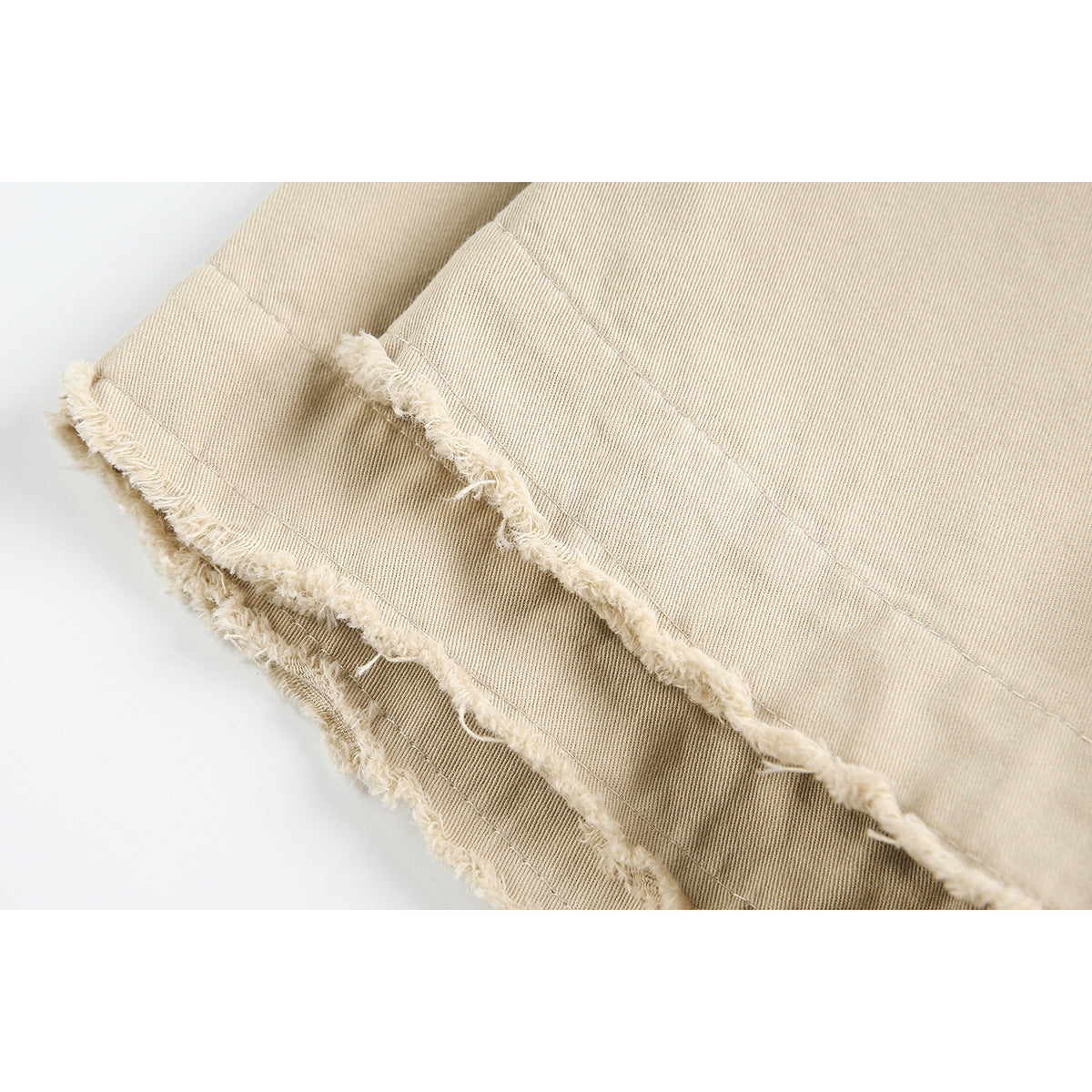 Close-up of a beige garment's double-stitched edge with a frayed raw hem.