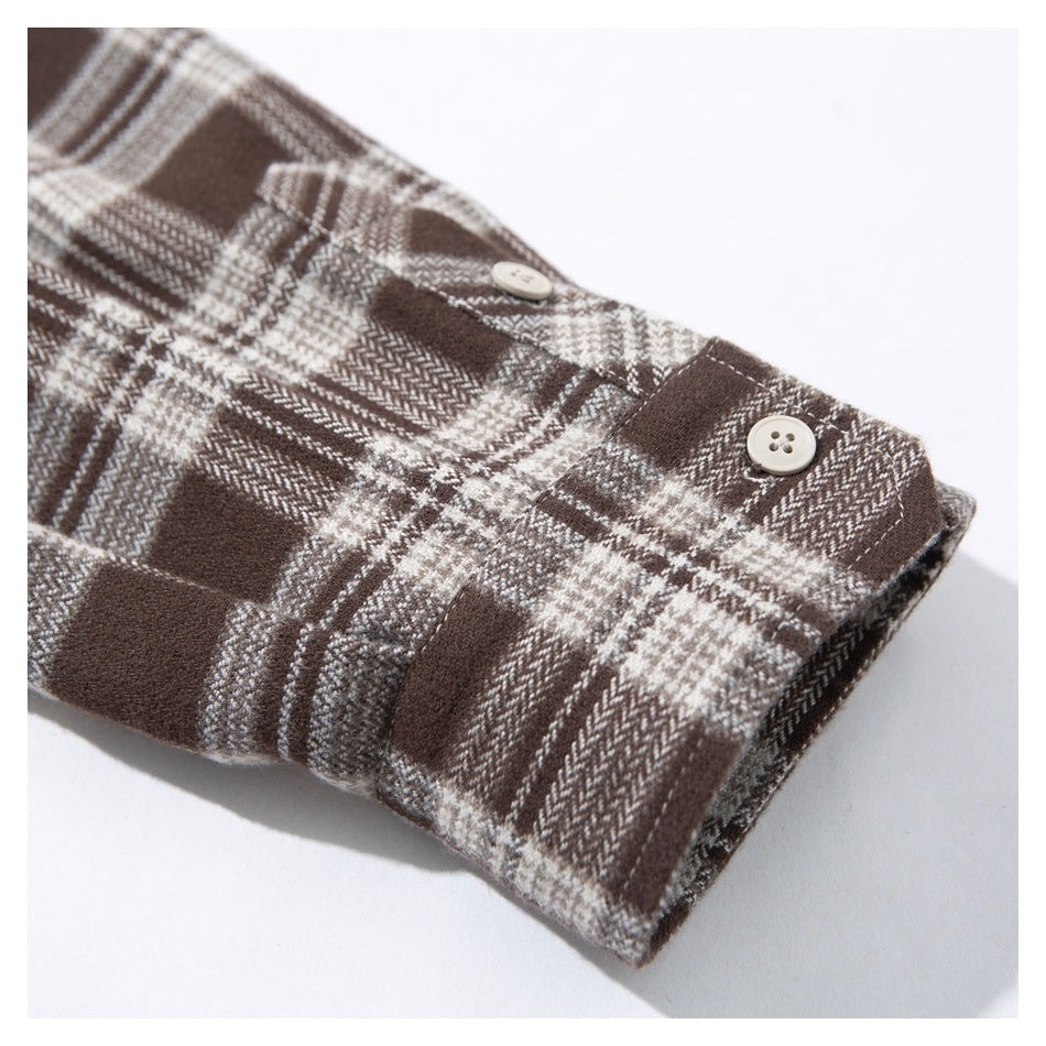 Close-up of the buttoned cuff of a brown and cream plaid shirt.