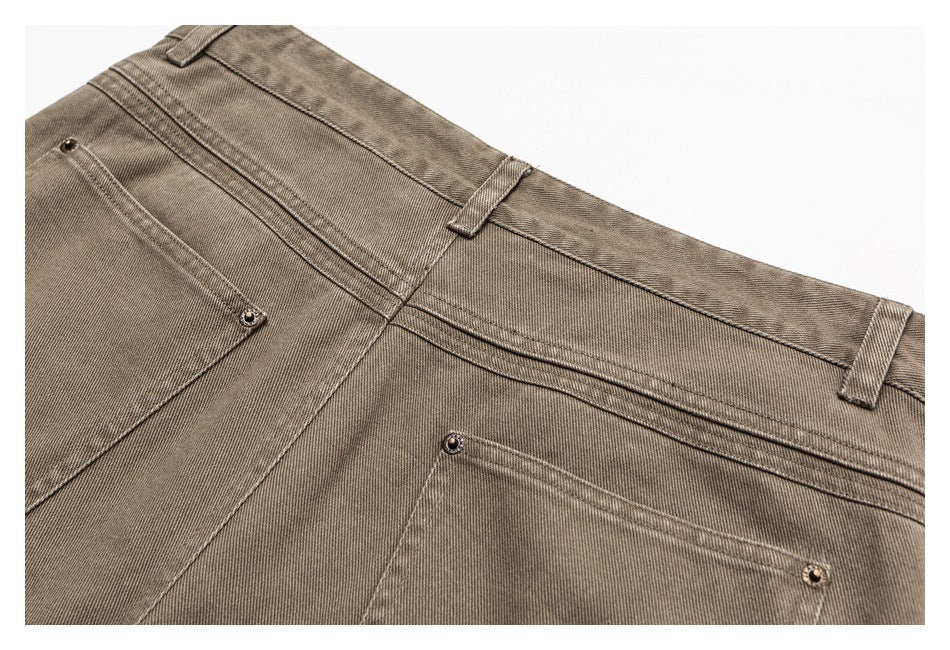 Close-up of taupe-gray jeans showing the waistband, belt loops, seams, and part of a pocket.