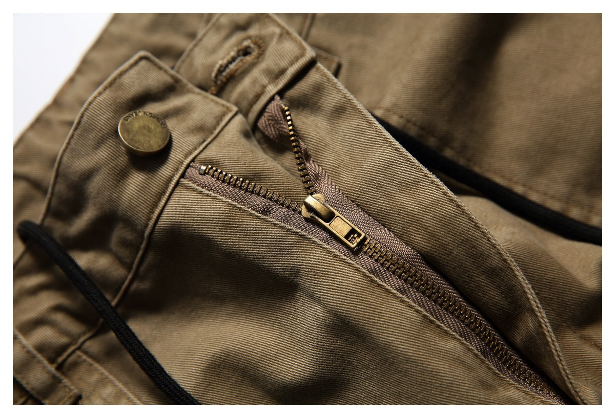 Close-up of the tan-brown trousers’ fly with an open brass zipper and button fastening.