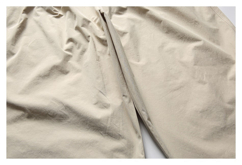 Close-up of beige trouser fabric and a long stitched seam between the legs.