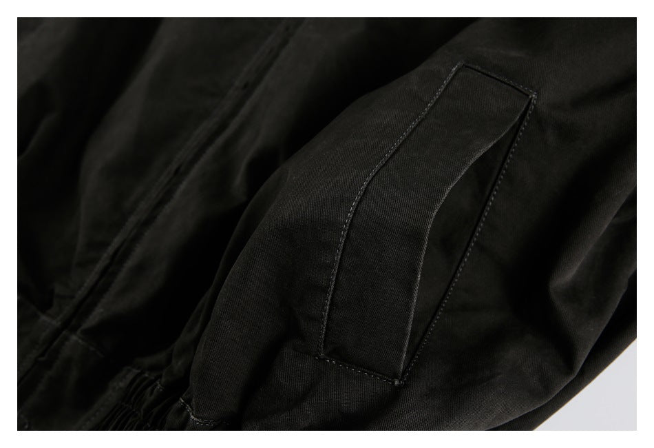 Close-up of a rectangular flap pocket on the black jacket's sleeve.