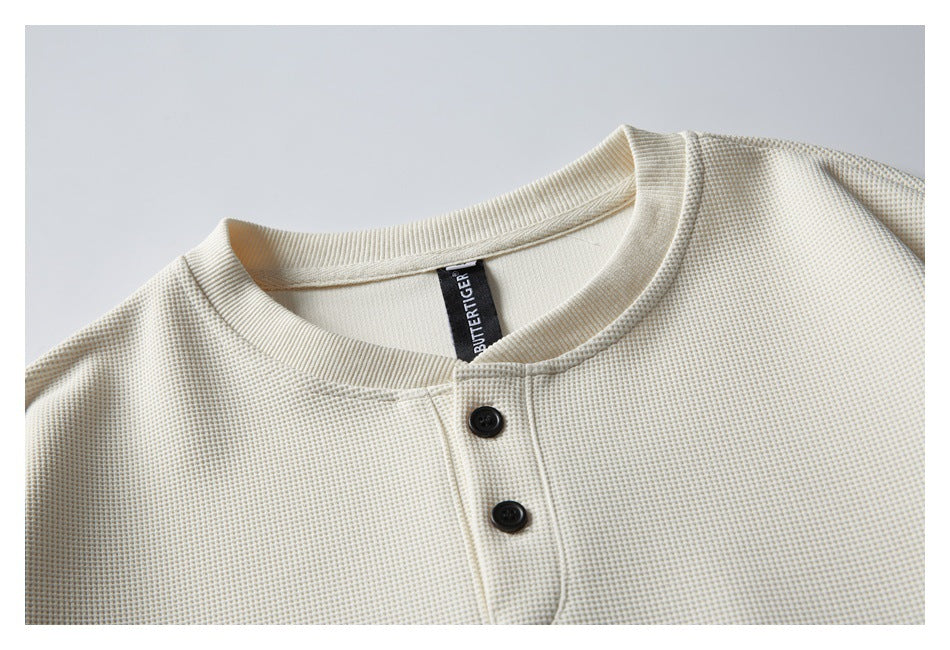 Close-up of the ivory sweatshirt's textured fabric, ribbed neckline and two dark buttons.