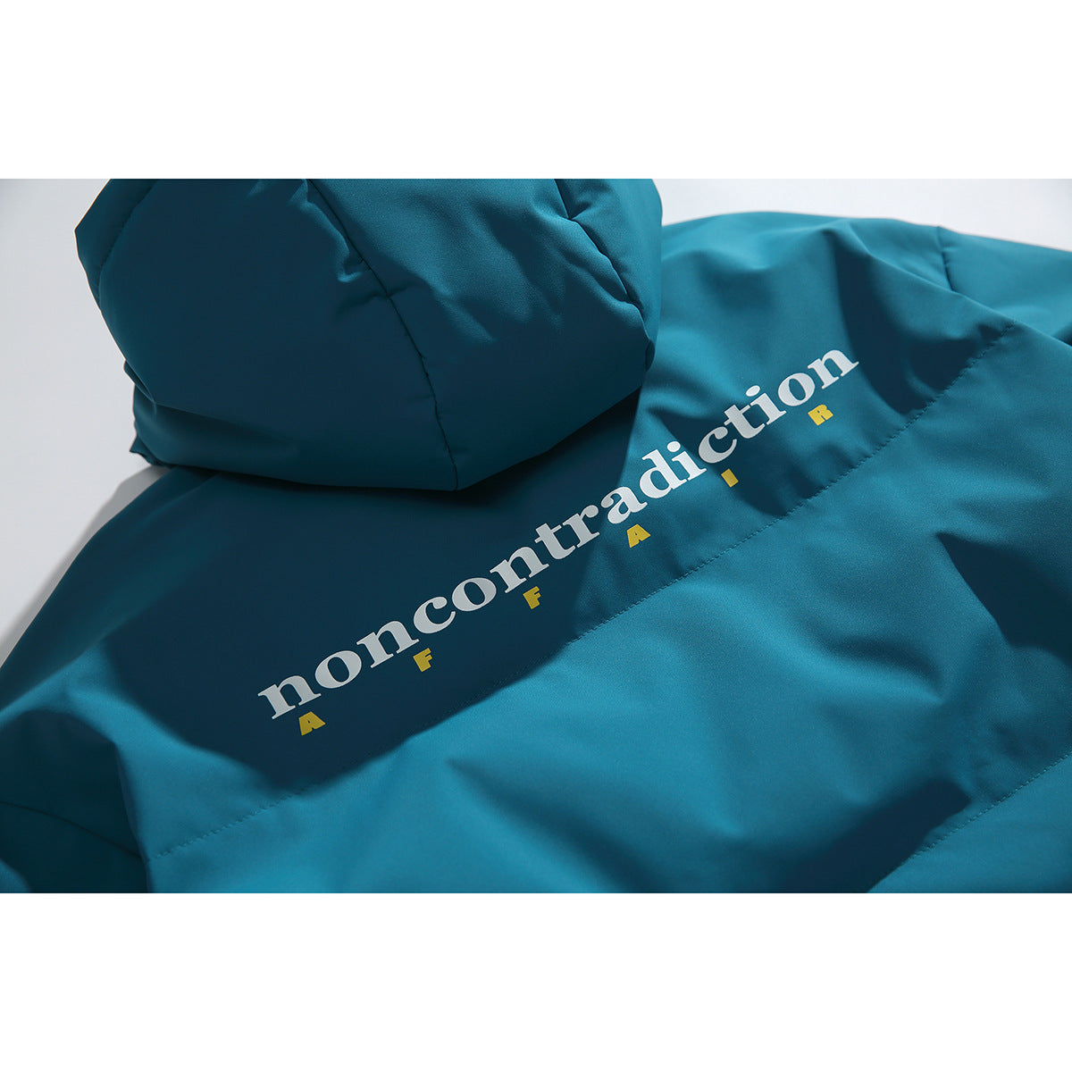 Close-up of a teal jacket back with white and yellow “noncontradiction” lettering.