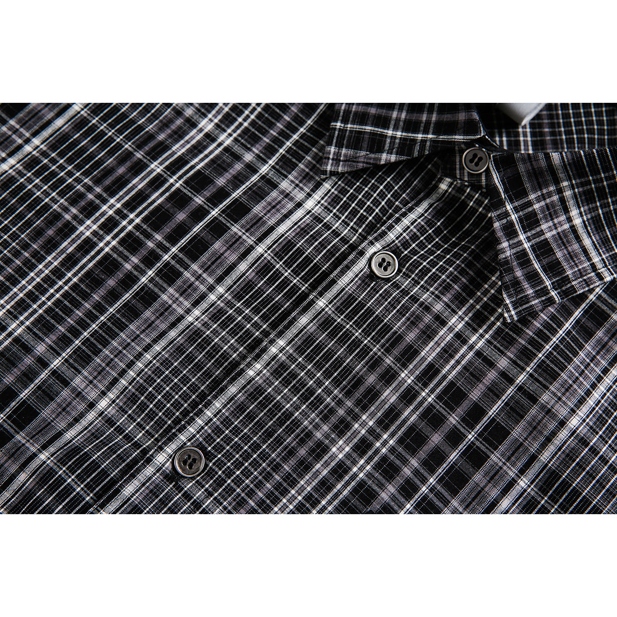 Close-up of the black-and-white plaid shirt front, showing its button placket and collar.