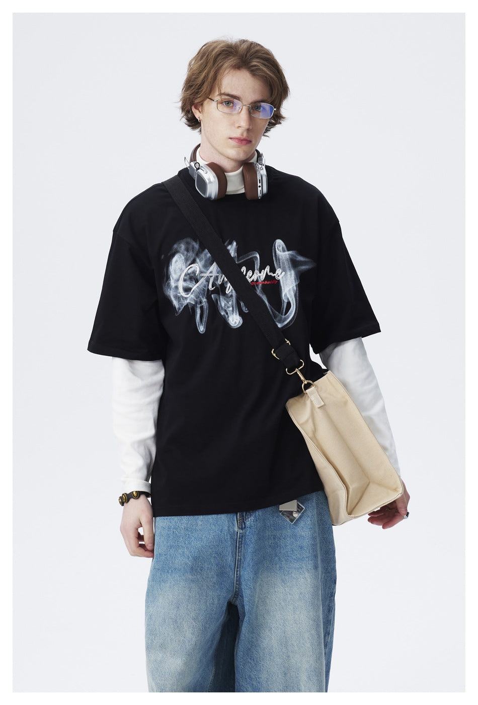 Closer view of a model wearing a black T-shirt with a large smoky graphic over white sleeves.