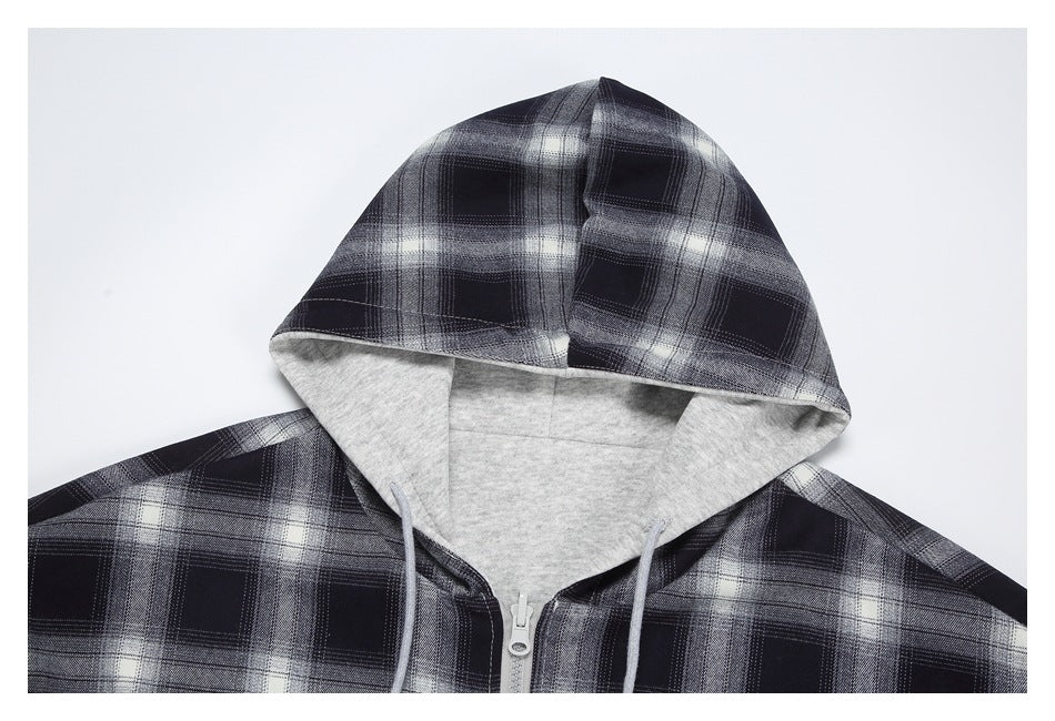 Close-up of a black, gray, and white plaid zip-up hoodie with a light gray lined hood and drawstrings.