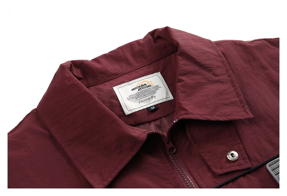 Close-up of a burgundy jacket collar, zipper, snap and sewn neck label.