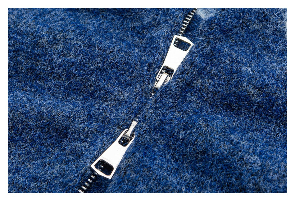 Close-up of a silver zipper set into textured blue knit fabric.