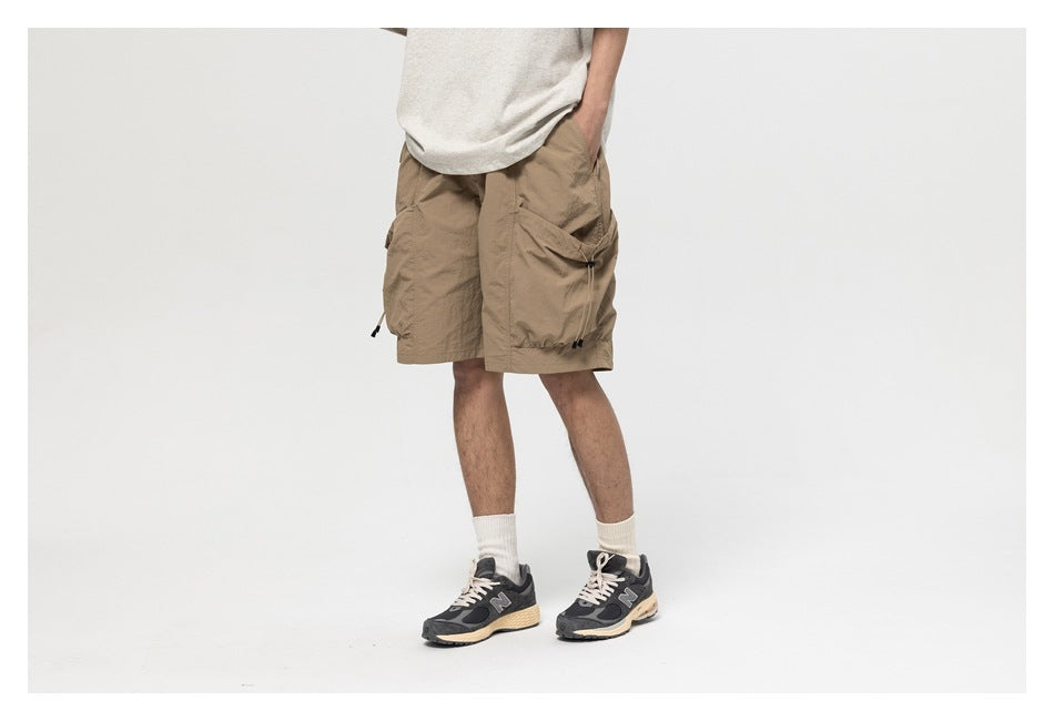 Model wearing khaki cargo shorts in a three-quarter view, one hand in pocket, showing the large side cargo pocket