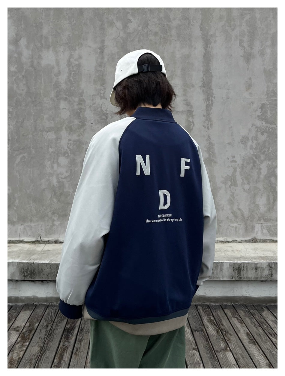 Back view of person in navy varsity jacket with gray-green sleeves and appliqué letters on the back