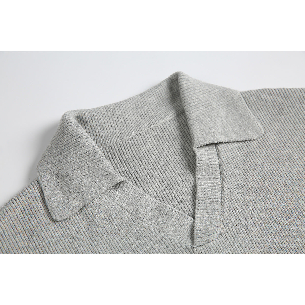 Close-up of a light gray rib-knit sweater’s folded collar and V-shaped neckline.