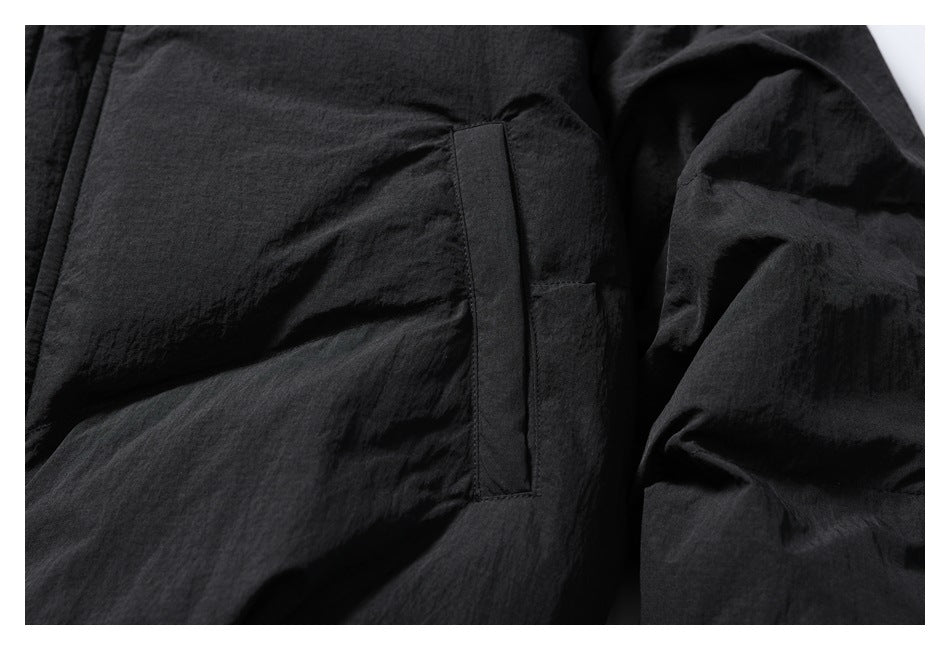 Close-up of a vertical welt pocket on the black jacket beside a gathered sleeve.