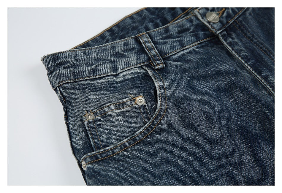 Close-up of dark blue washed jeans showing the front coin pocket, rivets, waistband, and belt loop.