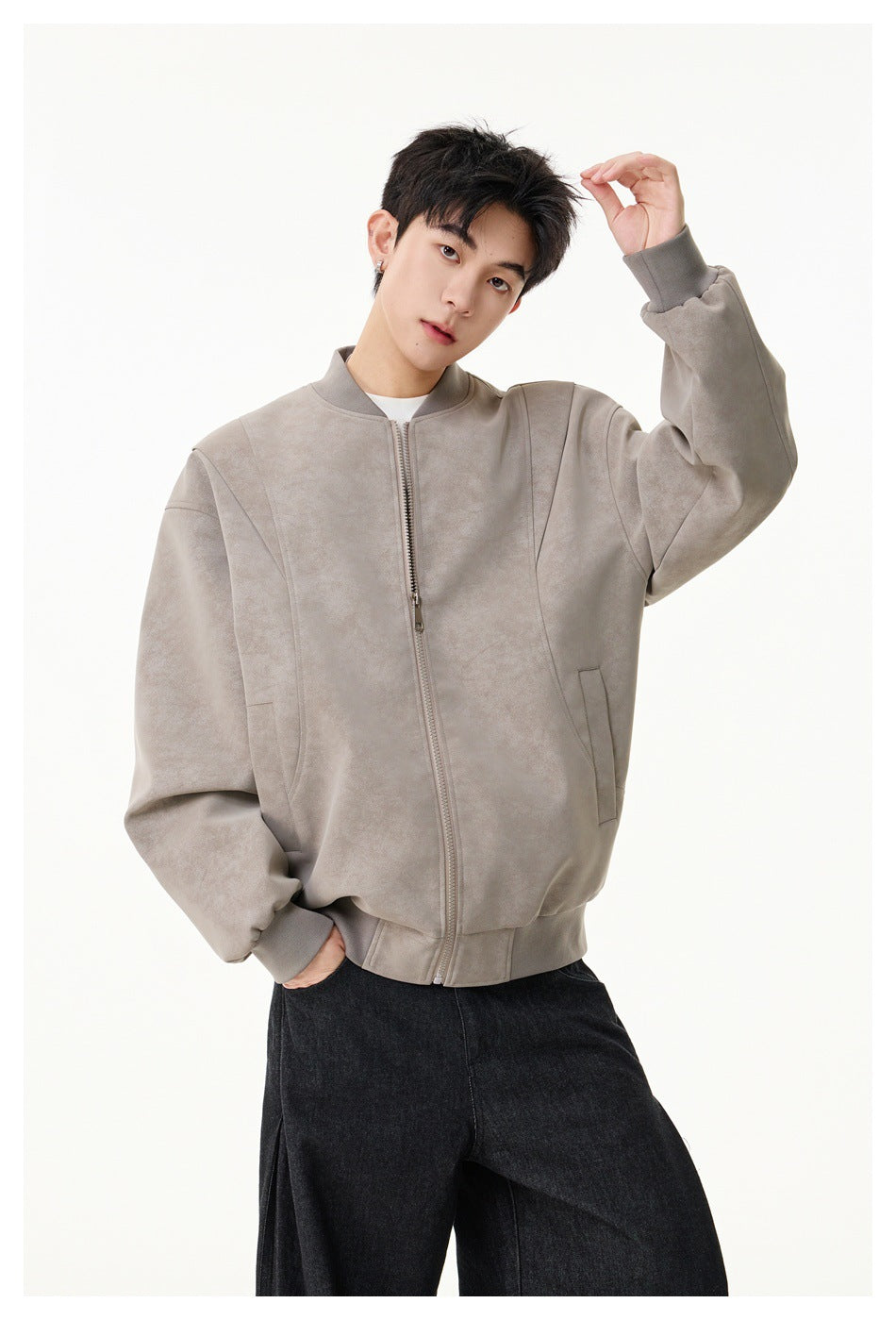 Model wearing a light taupe zip-front jacket with ribbed trims and visible side pockets.
