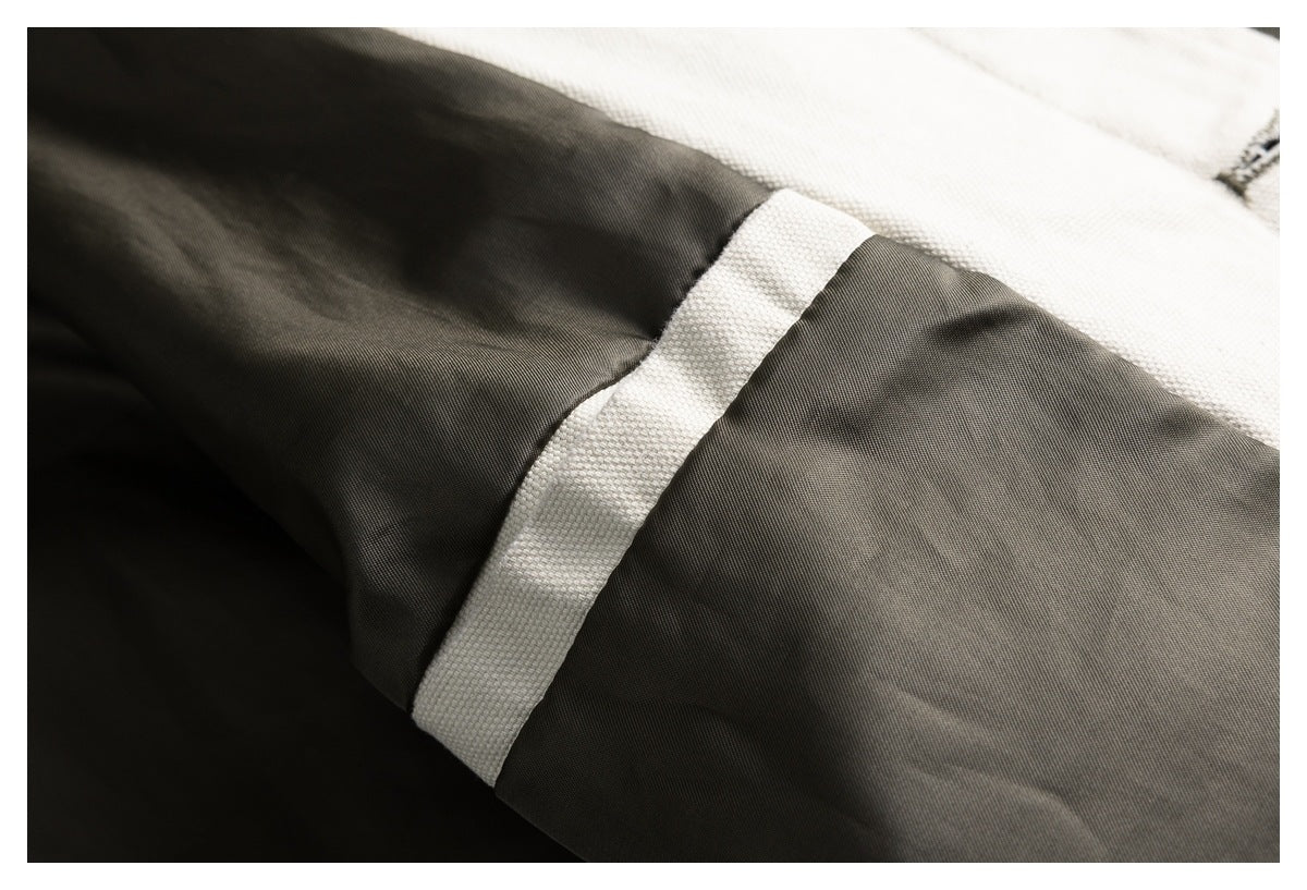 Close-up of dark olive jacket fabric and a cream contrasting inner seam or lining panel.