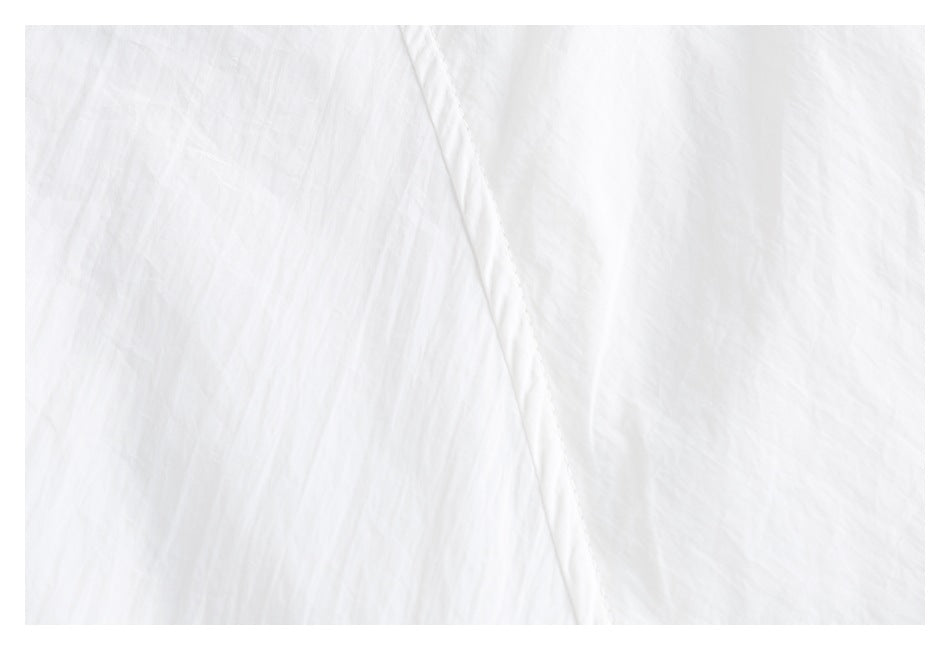 Close-up of white crinkled fabric with a stitched seam.