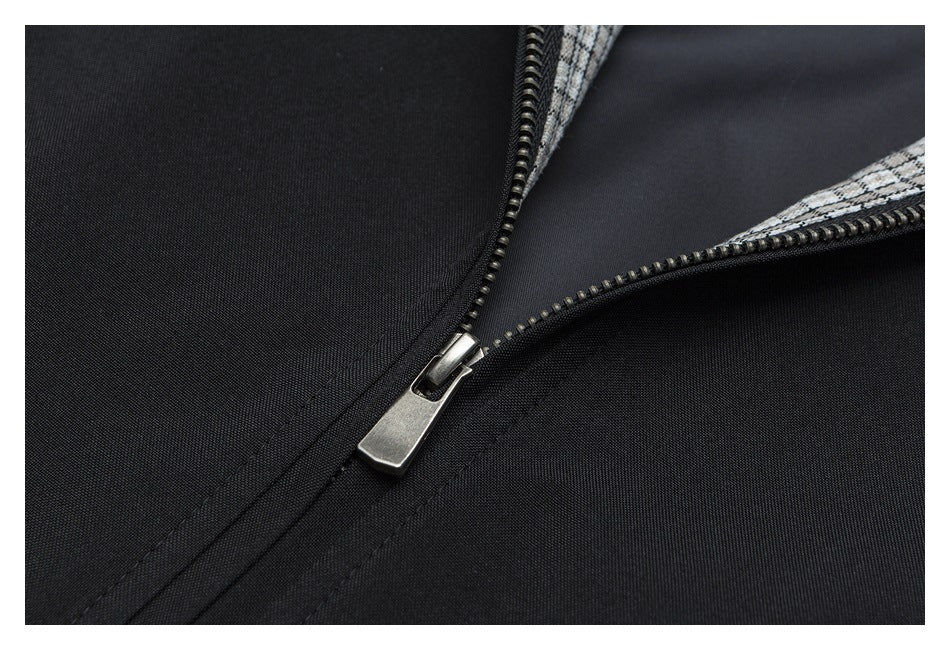 Close-up of a metal zipper on black fabric with a small section of gray checked trim.
