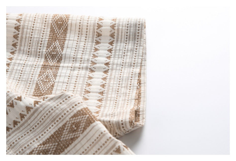 Close-up of cream fabric with tan geometric stripes and woven-looking motifs.