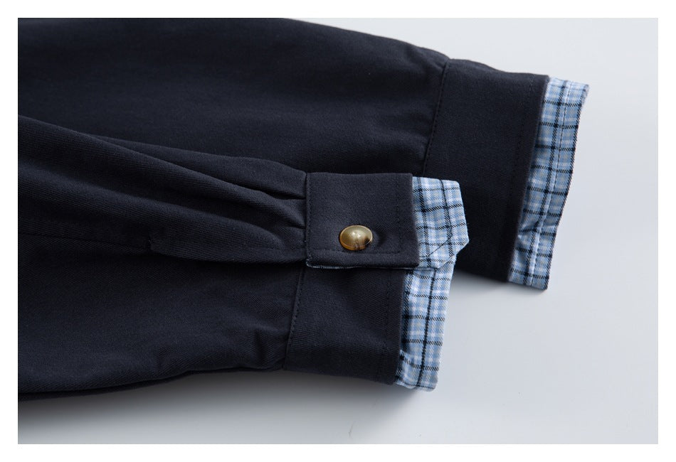 Dark navy sleeve cuff with a brass-colored button and blue plaid lining turned out.