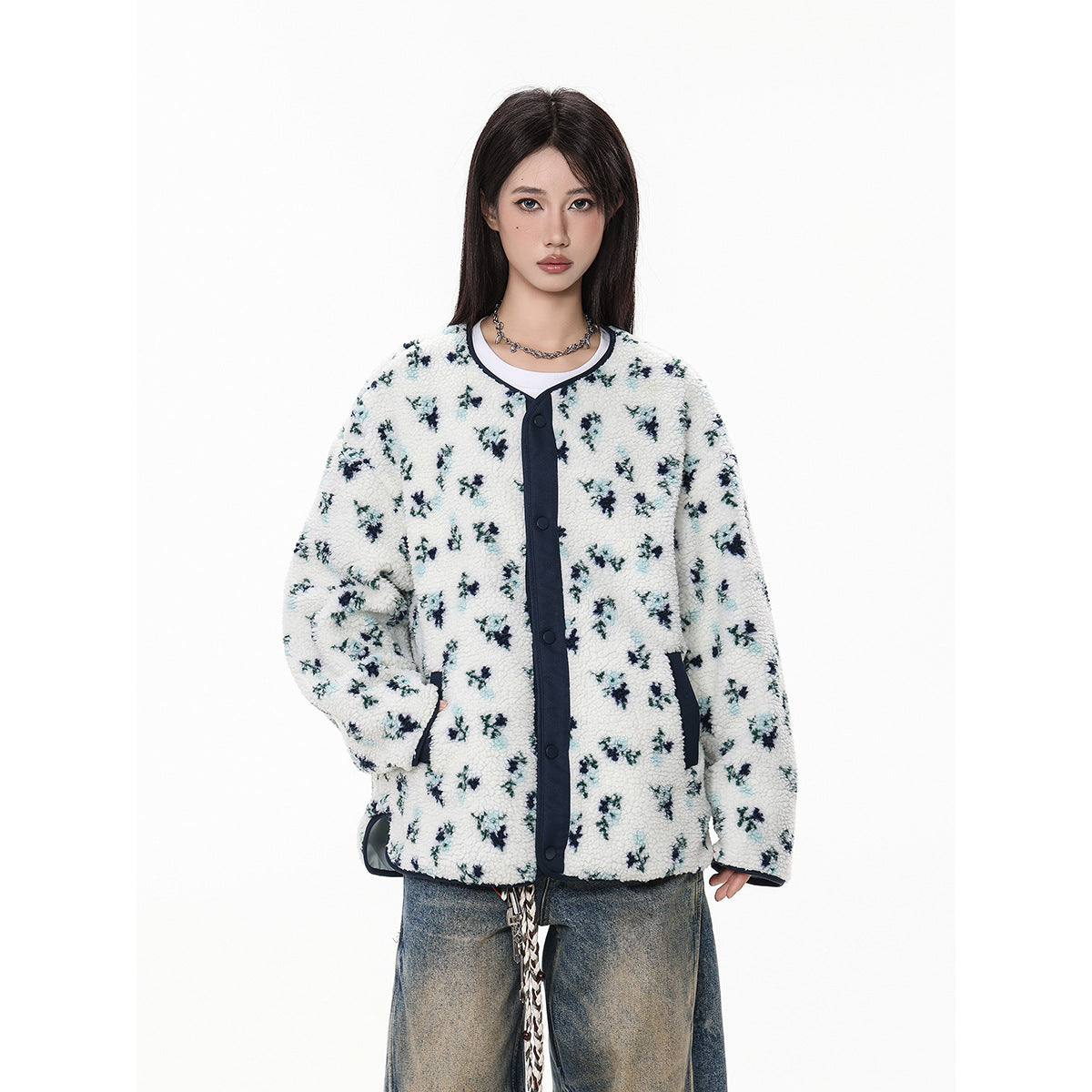 Model wearing a white floral fleece jacket with navy trim and snap buttons, paired with baggy jeans.