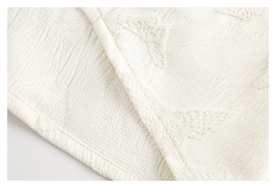 Close-up of ivory fabric panels with raised motifs and diagonal seam binding.
