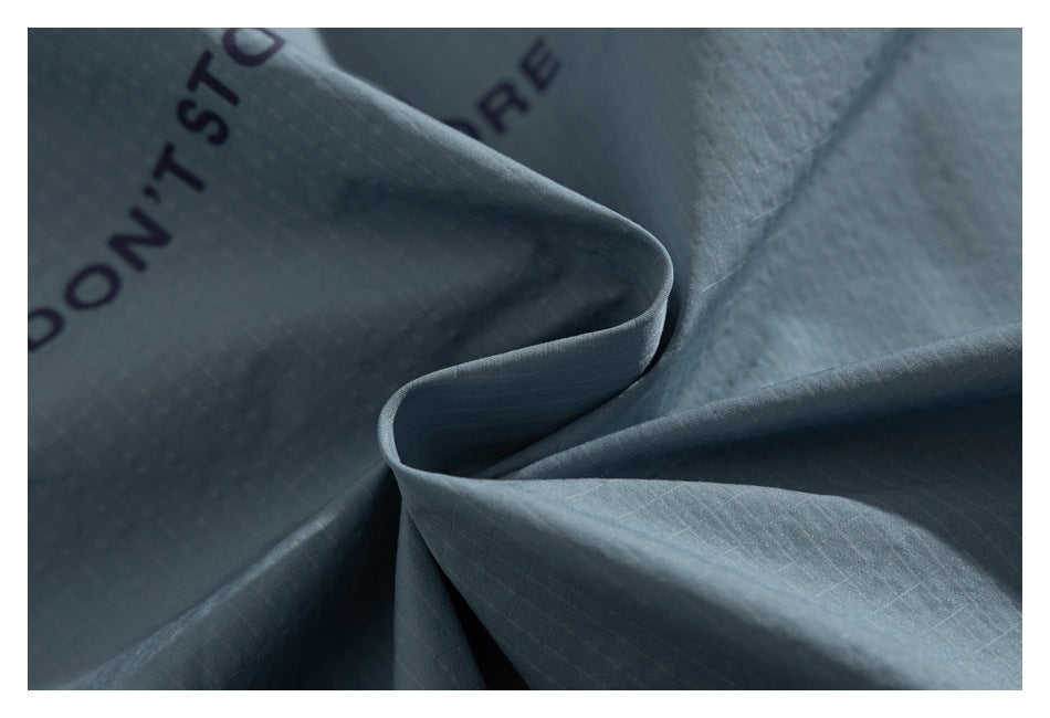 Close-up of folded blue-gray fabric with a subtle grid texture and partial black English lettering.