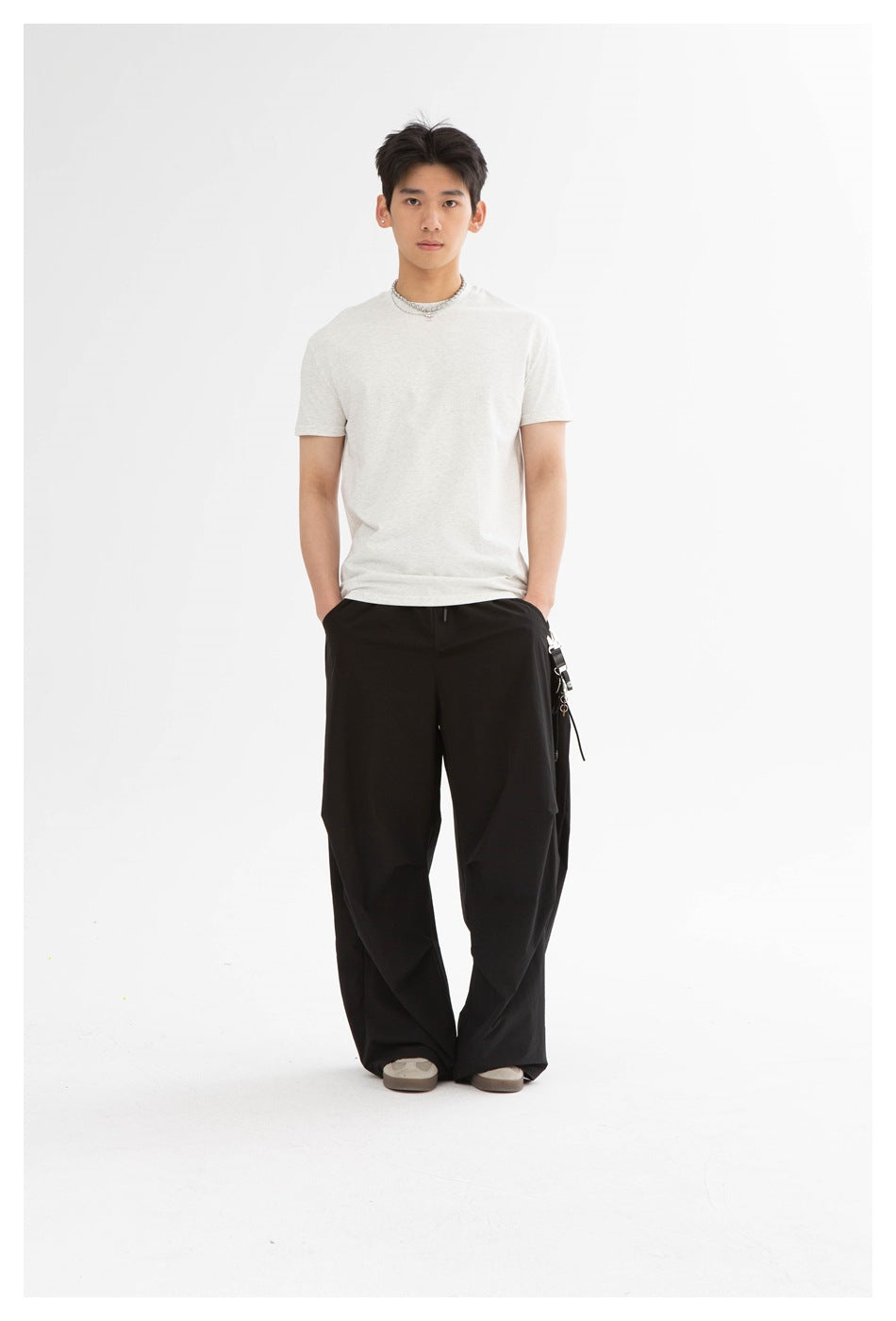 Front view of a model wearing a light heather-gray crew-neck T-shirt with wide black pants.