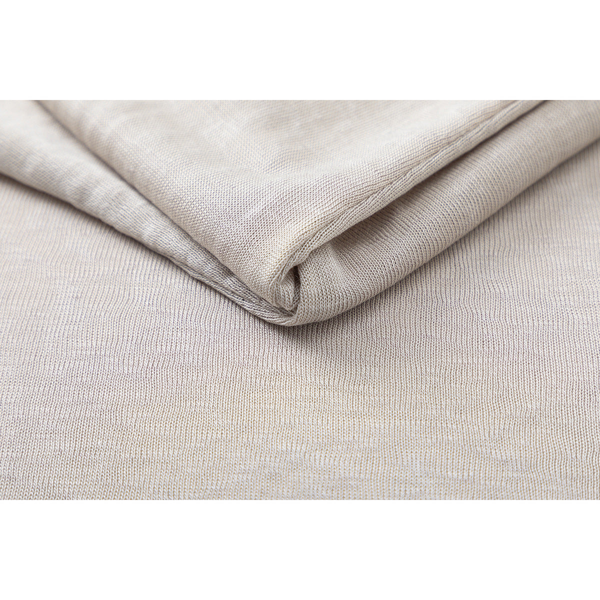 Close-up of light beige knit fabric folded to show its texture and edge.