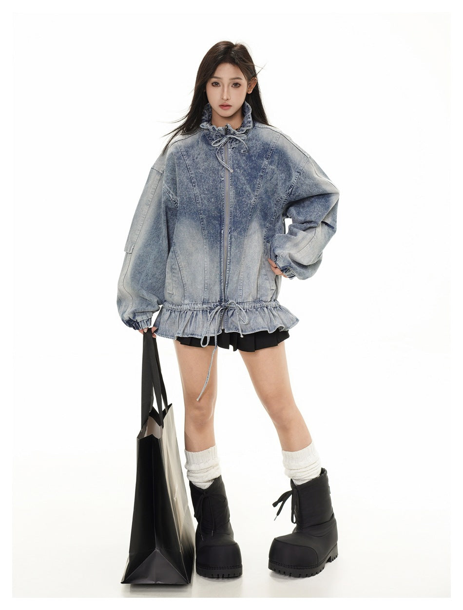 Full-length front view of a model in a washed blue denim jacket with voluminous sleeves, a drawstring waist and ruffled hem.
