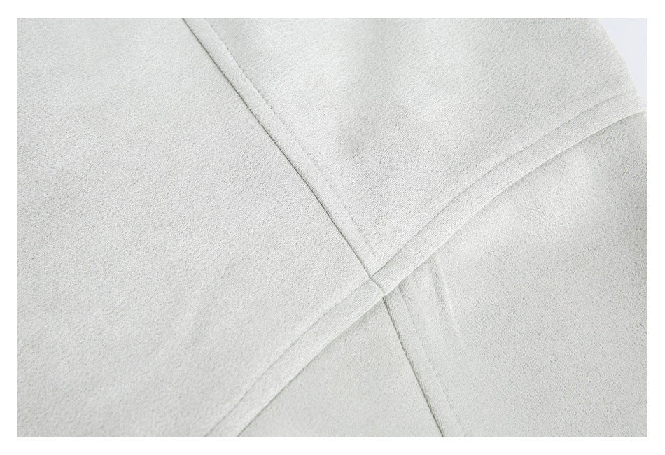 Close-up of intersecting seams on light gray jacket fabric.
