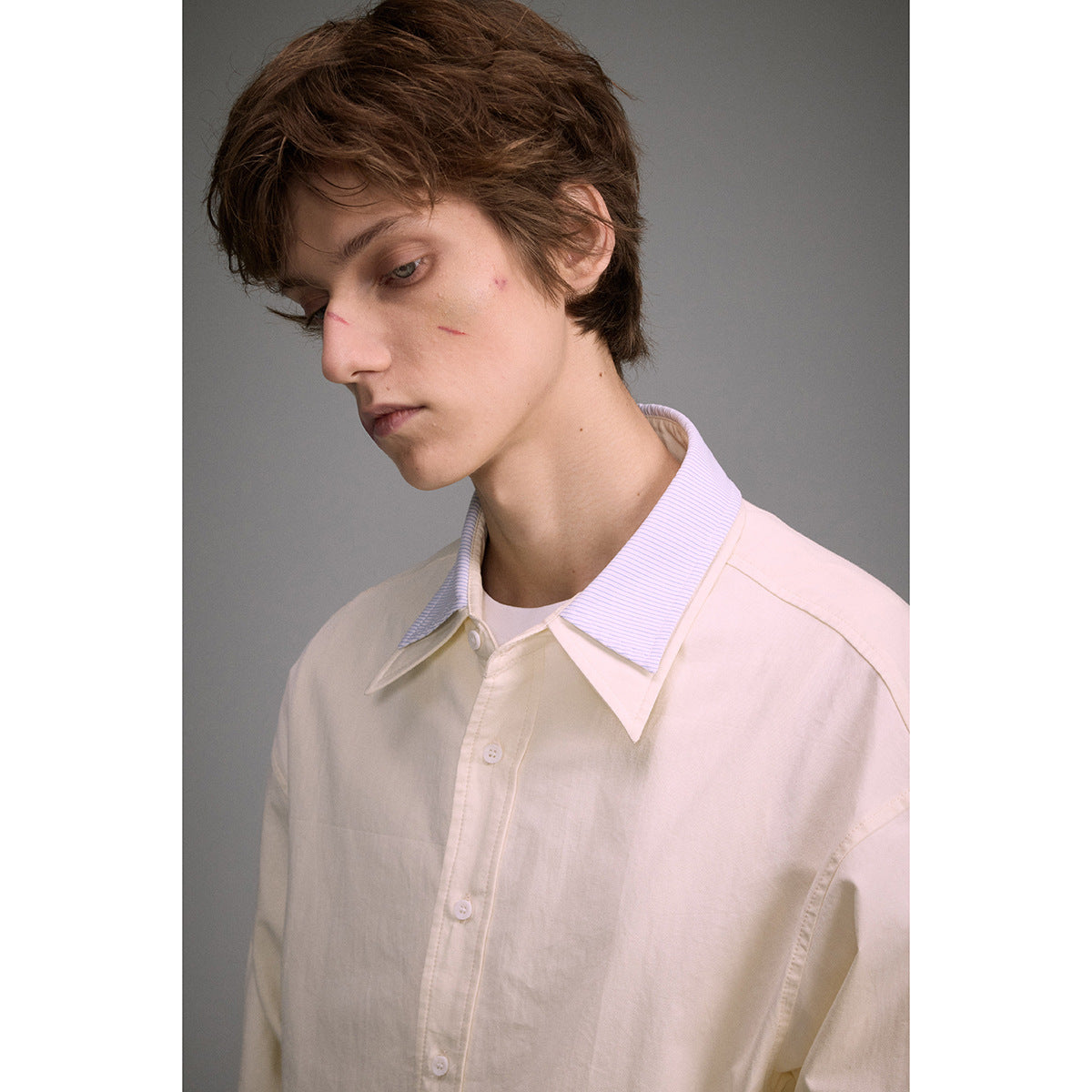 Close-up of an ivory shirt with a pointed collar featuring fine pale blue stripes.