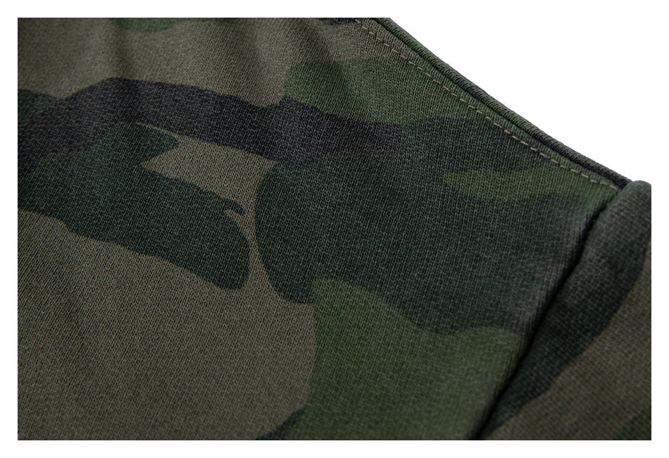 Close-up of dark green camouflage fabric with a curved stitched seam and folded edge.