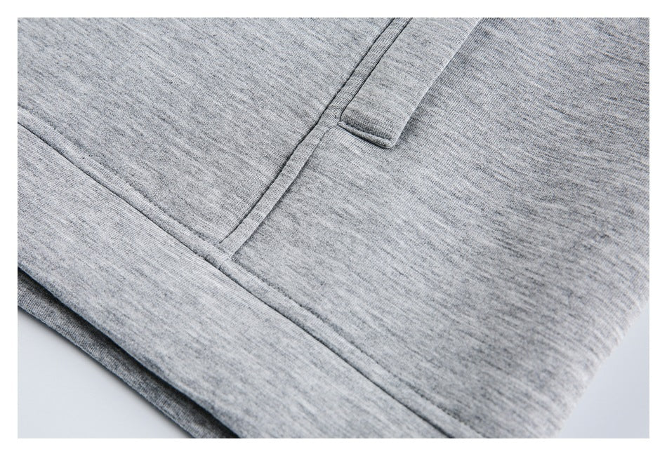 Close-up of heather gray knit fabric showing a seam, fabric tab, and folded edge.