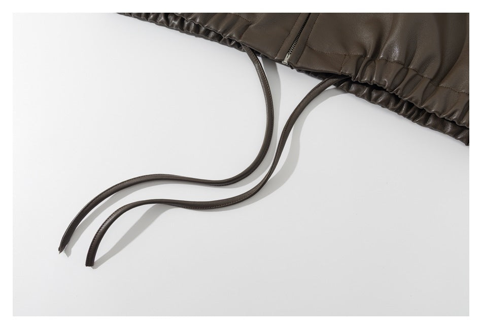 Close-up of a dark brown gathered garment edge with two long matching drawstrings.