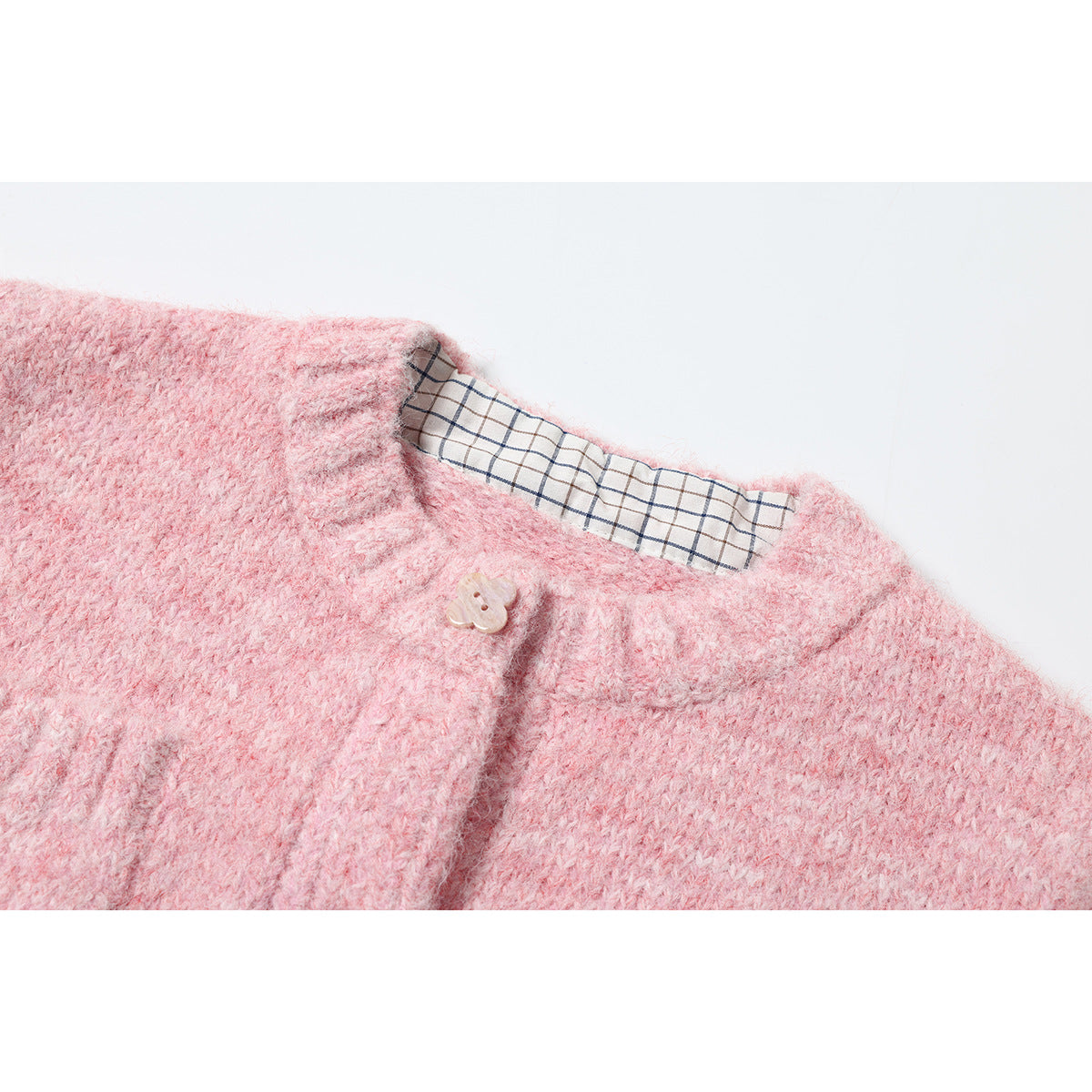 Close-up of a pink fuzzy knit garment neckline with a beige button and plaid lining.