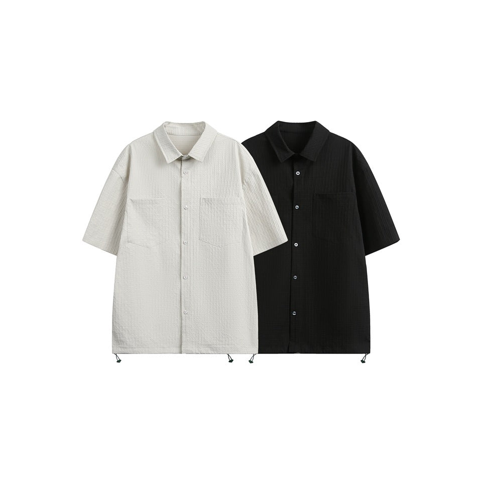 Two short-sleeve button-up shirts with chest pockets shown side by side in off-white and black.