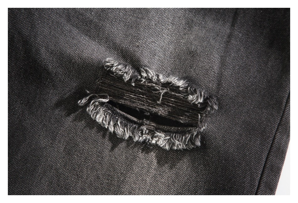 Close-up of a horizontal frayed tear in black denim.
