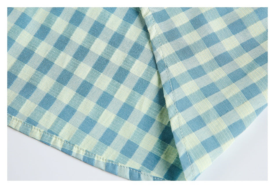 Close-up of the blue and pale yellow gingham shirt's stitched bottom hem and sleeve edge.