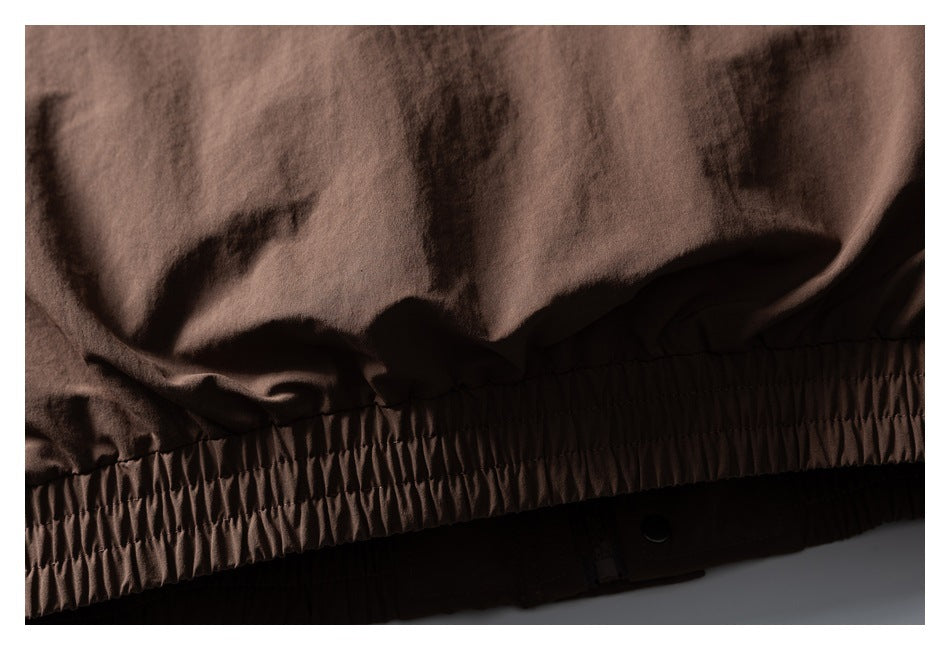 Close-up of the brown jacket's gathered elastic hem with a dark snap closure below.