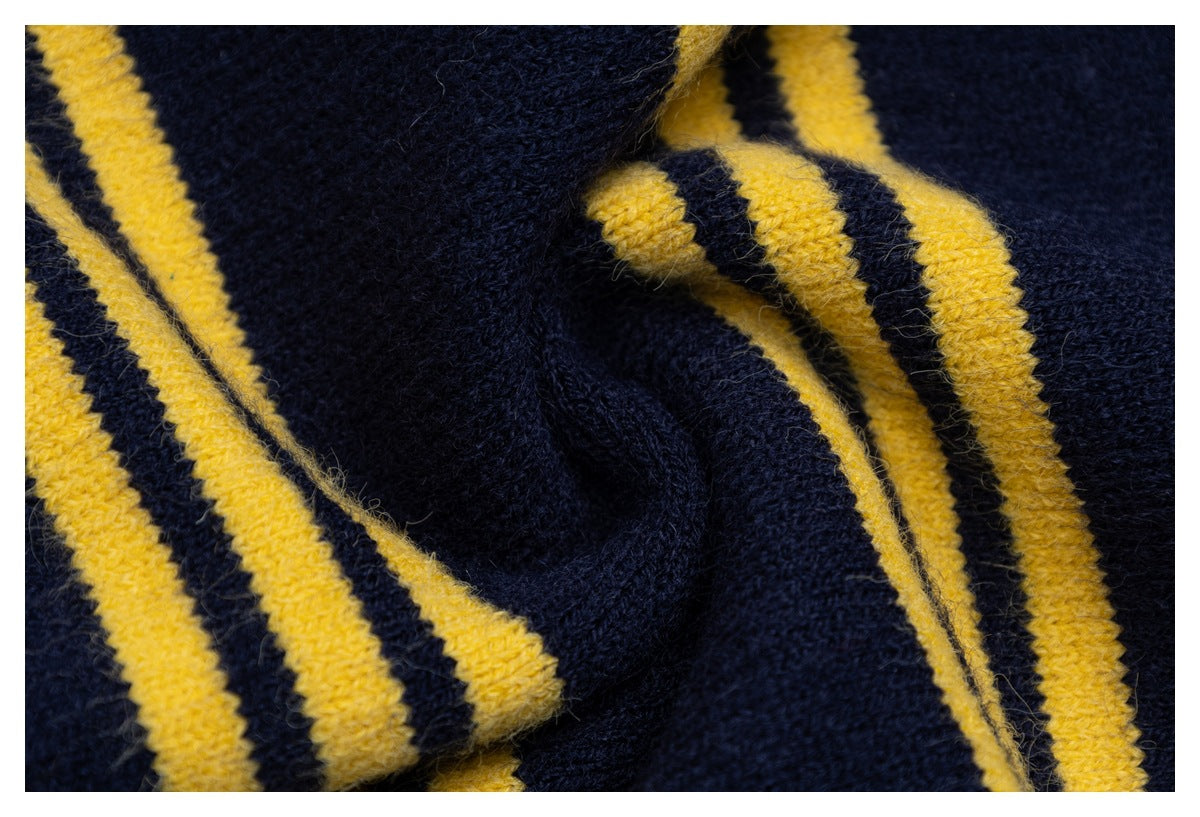 Close-up of navy knit fabric and mustard-yellow stripe detailing around a folded garment edge.