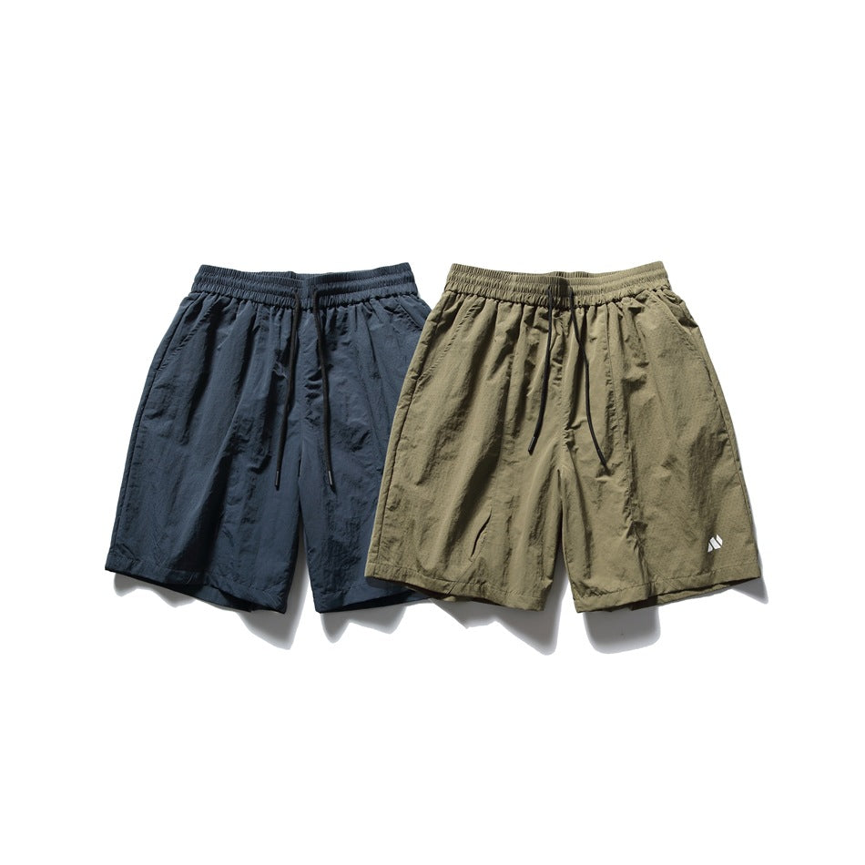 Two pairs of loose shorts shown flat, one dark navy and one olive, both with elastic waistbands and drawstrings.