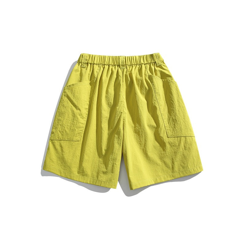 Bright yellow shorts with an elastic waistband and large patch pockets on both sides, shown against white.