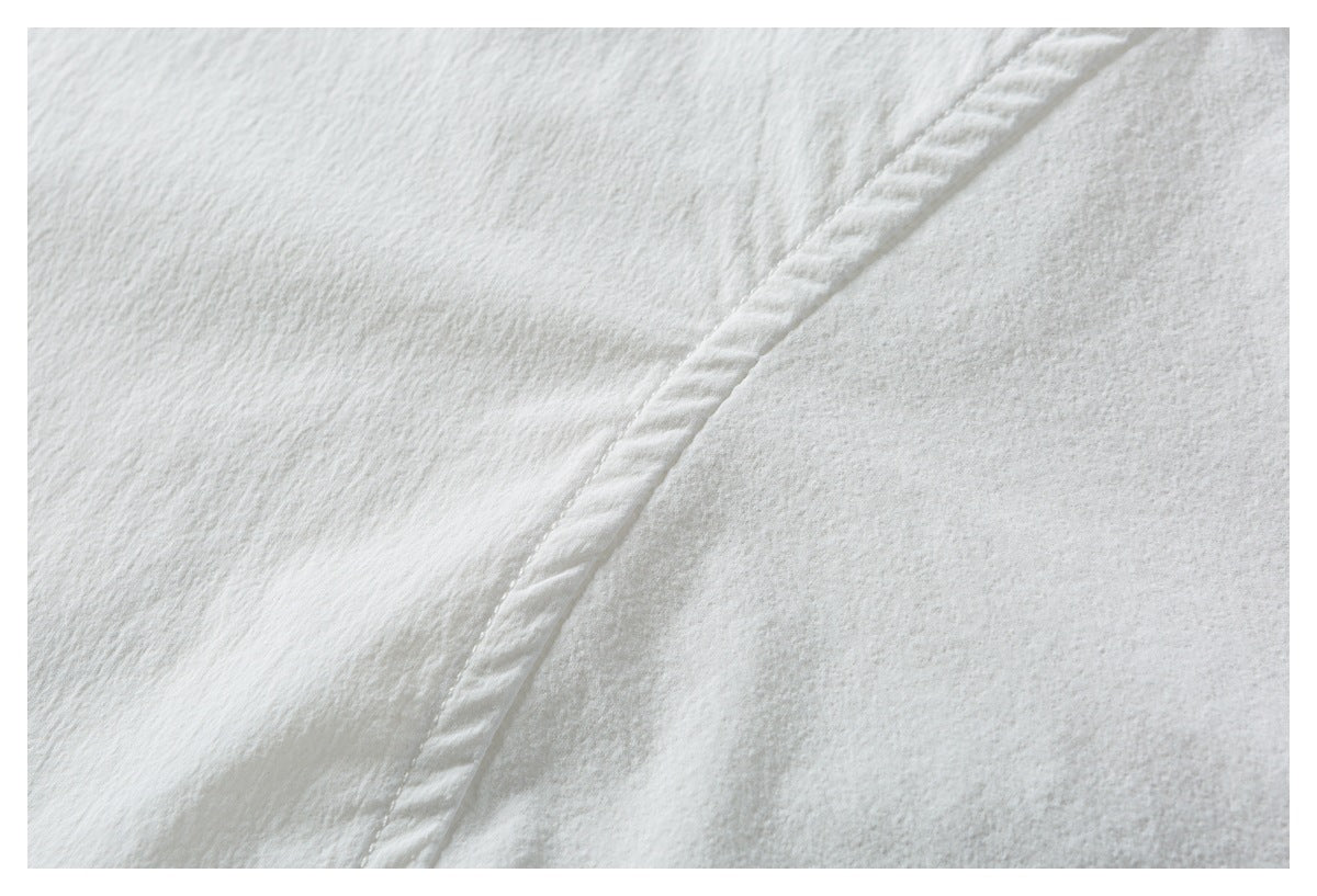 Close-up of white textured fabric and a curved stitched seam.