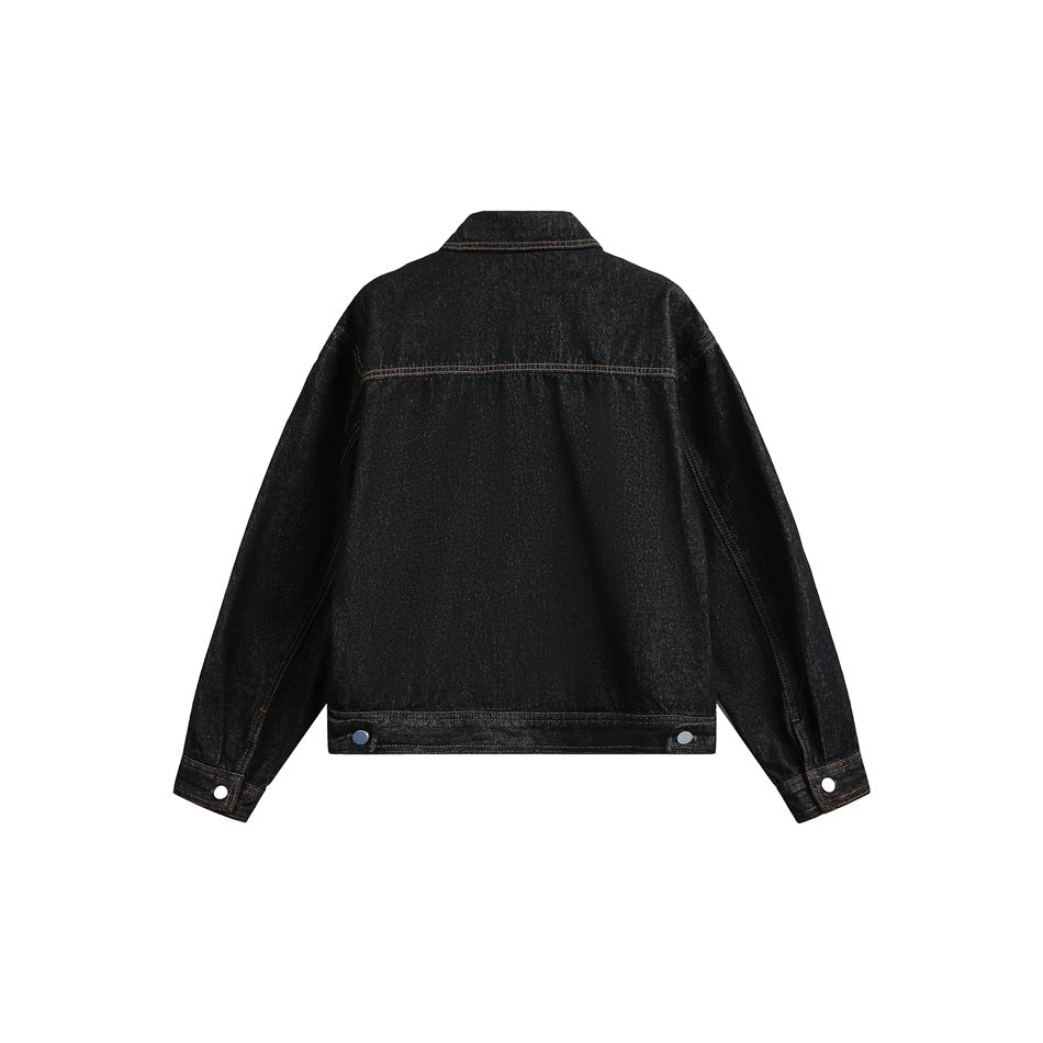 Back view of black washed denim jacket showing yoke seam, tan stitching, hem button tabs and buttoned cuffs