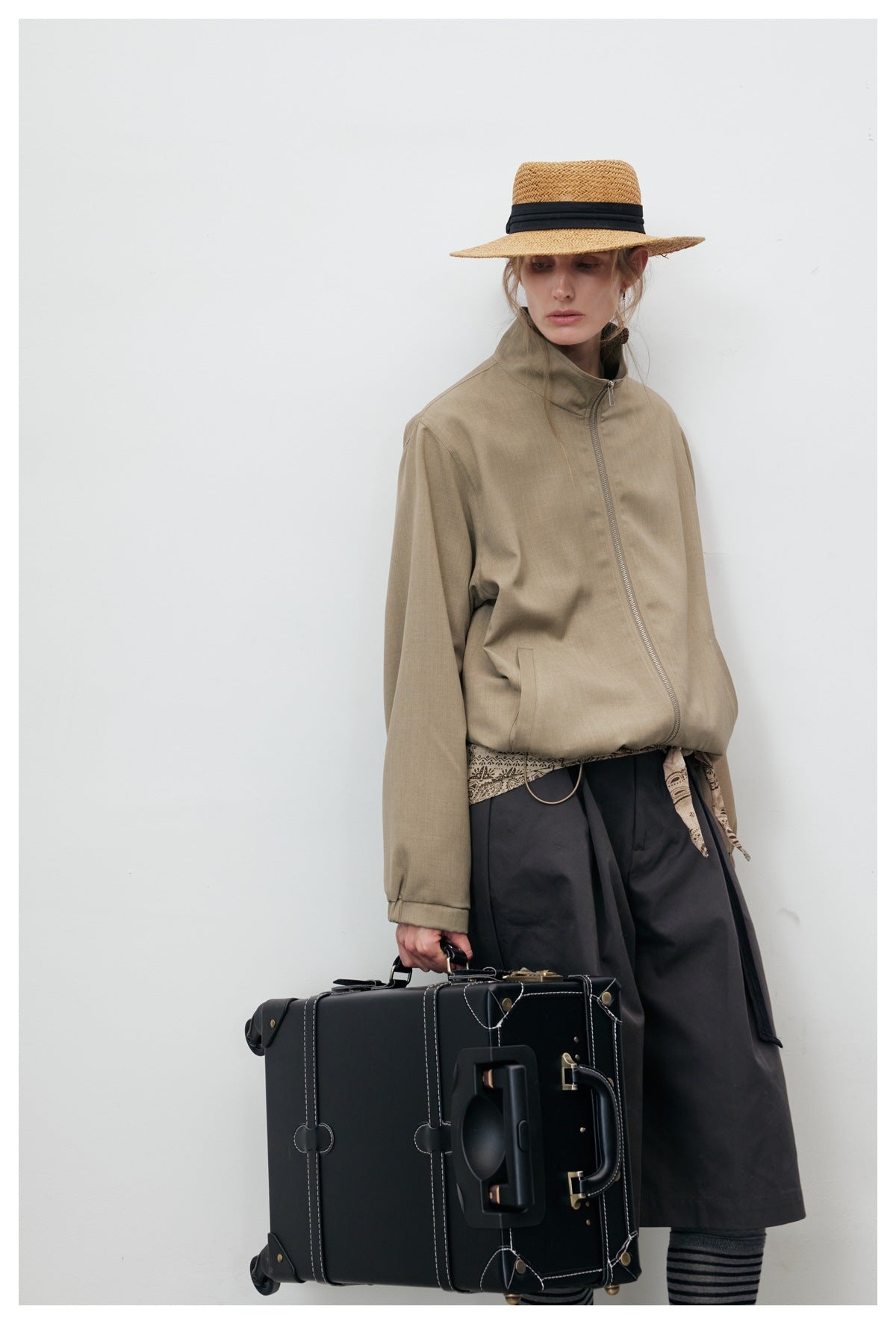 Closer view of a model wearing a taupe jacket with a high stand collar, front zipper and long sleeves.
