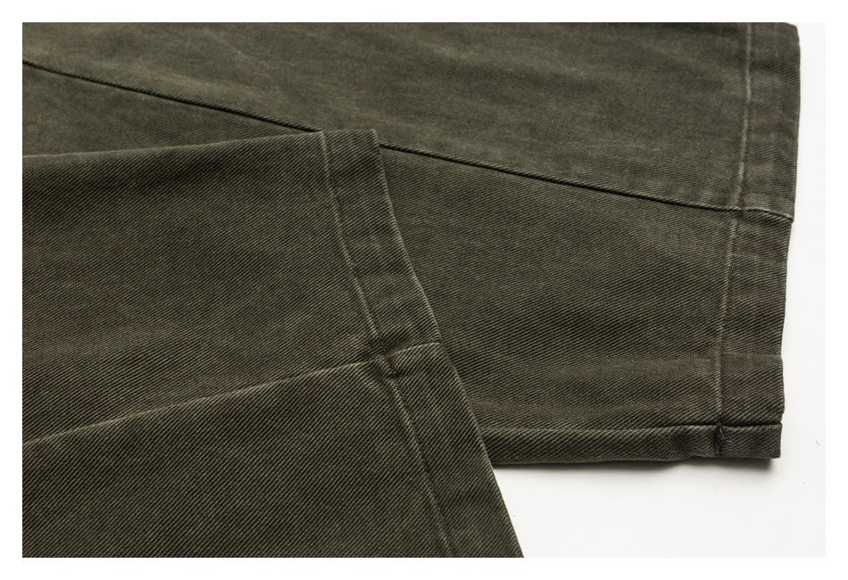 Close-up of dark olive trouser legs showing stitched hems and overlapping fabric panels.